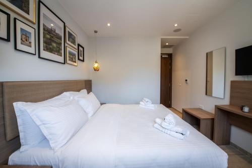 a bedroom with a white bed with two towels on it at Bliss Boutique Living in Xagħra