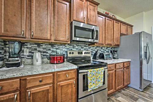 a kitchen with wooden cabinets and a stove and refrigerator at Jax Home with Yard - 10 Mi to Adventure Landing! in Jacksonville