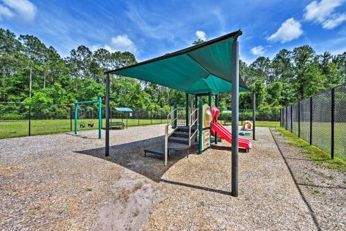 a playground with a green canopy and a slide at Jax Home with Yard - 10 Mi to Adventure Landing! in Jacksonville