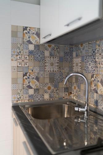 a kitchen with a sink and a tile wall at Kalos Casa Vacanza in Salice Salentino