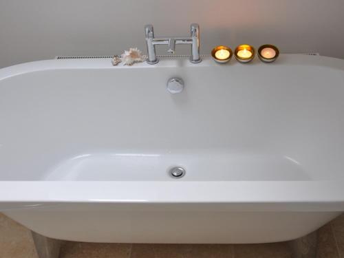 The Hayloft B and B في نيوبري: حوض استحمام أبيض في الحمام مع الشموع