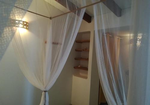 a bedroom with a white curtain and a shelf at Nos Kasa Povoaçao Velha in Cabeçadas