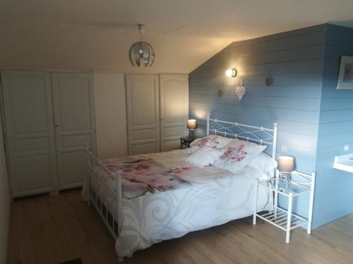 um quarto com uma cama branca e uma parede azul em Les Arums de Fondeminjean em Vertheuil-en-Médoc