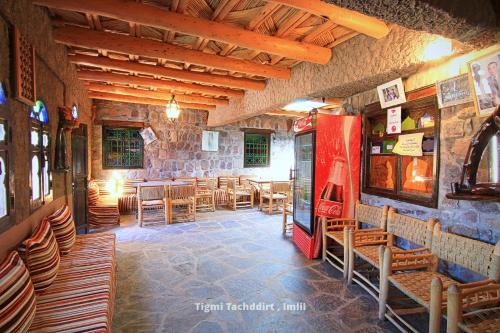 a restaurant with tables and chairs and a red refrigerator at Tigmi Tachddirt in Tacheddirt