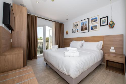 a bedroom with a large white bed and a television at Bliss Boutique Living in Xagħra