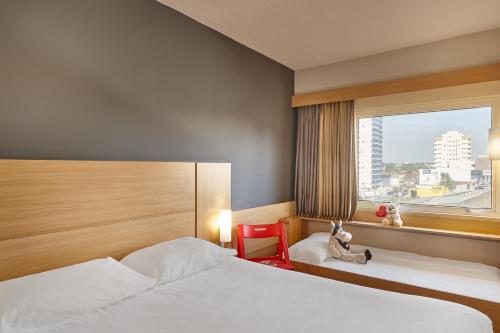 a hotel room with two beds and a window at ibis Sao Jose dos Campos Dutra in São José dos Campos