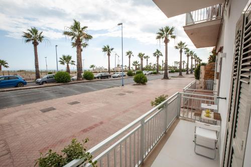 a balcony with palm trees and a street at Casa Timone in San Leone