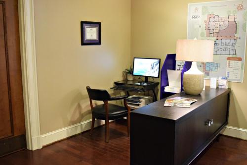 a room with a desk with a lamp and a chair at JH Adams Inn, Trademark Collection by Wyndham in High Point
