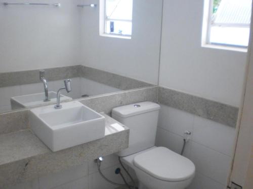 a white bathroom with a sink and a toilet at Hotel Abrolhos in Nova Viçosa