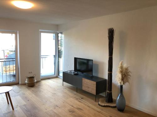 a living room with a flat screen tv and a table at Modernes Apartment in Gondelsheim