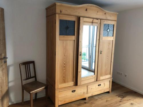 a wooden cabinet with a window next to a chair at Modernes Apartment in Gondelsheim