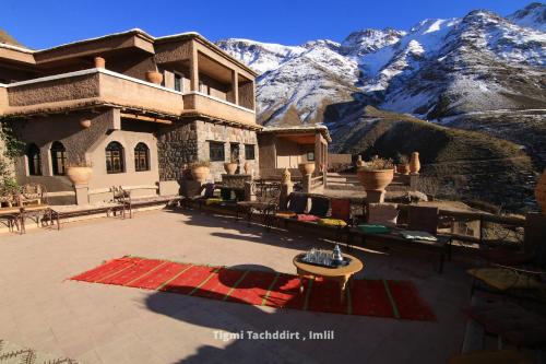 a building with a patio with mountains in the background at Tigmi Tachddirt in Tacheddirt