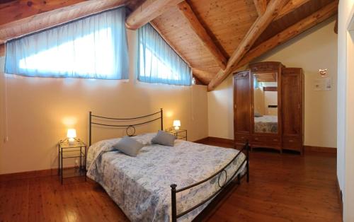 a bedroom with a large bed and two windows at Agriturismo IL FRA' in Tigliole