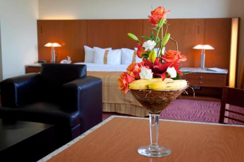 un jarrón de flores sobre una mesa en una habitación de hotel en Holiday Inn Puebla Finsa, an IHG Hotel, en Puebla