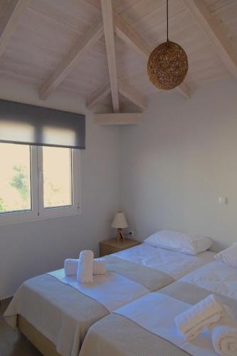two beds in a white bedroom with a chandelier at Vasiliki Residence in Pylos