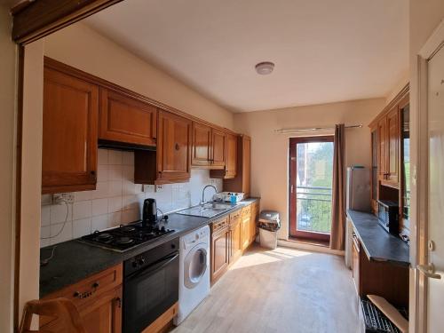 eine Küche mit Holzschränken, einer Waschmaschine und einem Trockner in der Unterkunft Carnarvon Street City Centre Apartment in Glasgow