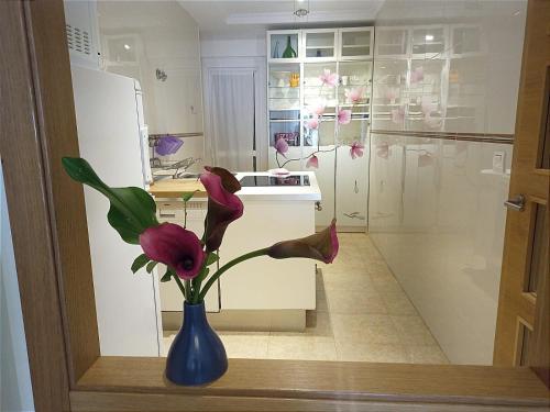 eine blaue Vase mit rosa Blumen in der Küche in der Unterkunft A&L Playa in Viveiro