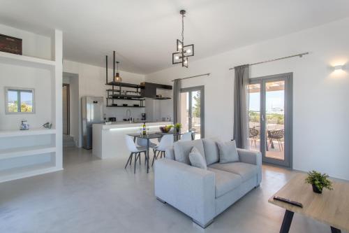 ein Wohnzimmer und eine Küche mit einem Sofa und einem Tisch in der Unterkunft Bluebell Resort Villa SUNSET in Kampos Paros
