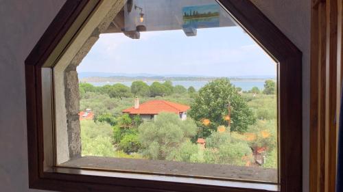a window with a view of a house in a field at Thea Thalassa in Vourvourou