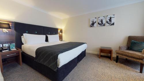 a hotel room with a bed and a chair at Holiday Inn London Kensington High St. by IHG in London