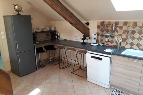 a kitchen with a counter with stools and a refrigerator at Villa Sauna Tout Confort Pleine Campagne in Ladon