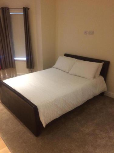 a bedroom with a bed with white sheets and a window at Stafford apartments in Stafford