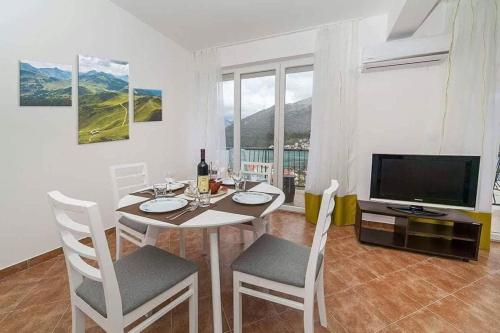 a dining room with a table with chairs and a television at Villa Angel in Kamenari