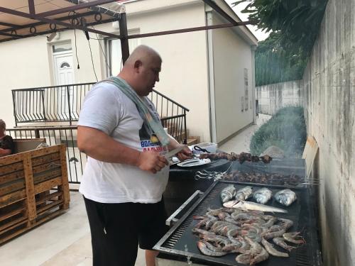 a man is cooking food on a grill at Villa Angel in Kamenari