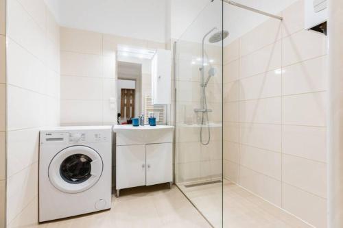 a white bathroom with a washing machine and a shower at Family apartment next to Danube river in Vienna