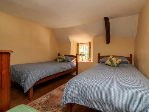 1 dormitorio con 2 camas y ventana en Bell Buoy Cottage, en Bude