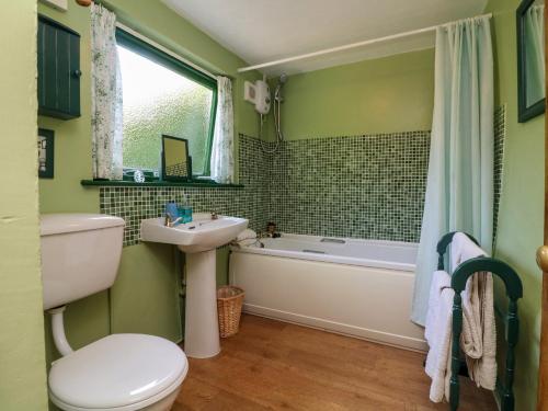 a bathroom with a sink and a tub and a toilet at Bell Buoy Cottage in Bude