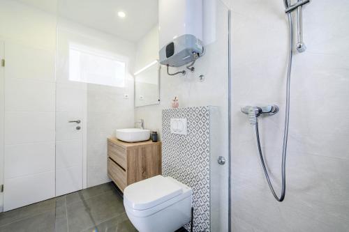 ein weißes Badezimmer mit Toilette und Dusche in der Unterkunft Apartment Seaside in Zaboric