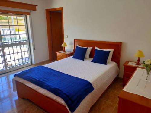 een slaapkamer met een groot bed met blauwe kussens bij Casa da Sao in Nazaré