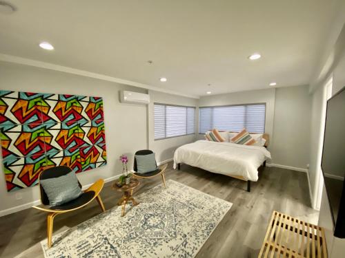 長灘的住宿－Superb Long Beach House Steps to Sand w/ Roof Deck，一间卧室配有一张床、两把椅子和一幅画