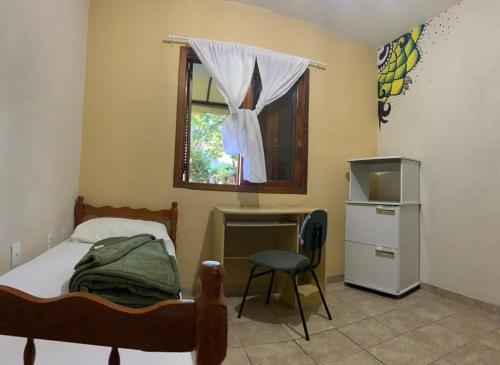 a bedroom with a bed and a desk and a window at Pousada Agronomia in Porto Alegre