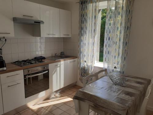 une cuisine avec des armoires blanches, une table et une fenêtre dans l'établissement Maison au pays D' Aristide Bruand - Rose-Marie-Courtenay, à Courtenay