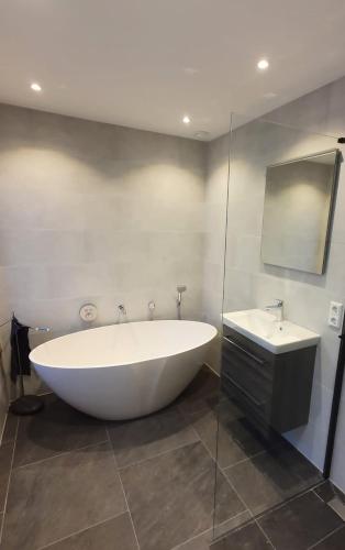 a large white tub in a bathroom with a sink at Biedebure in Colijnsplaat