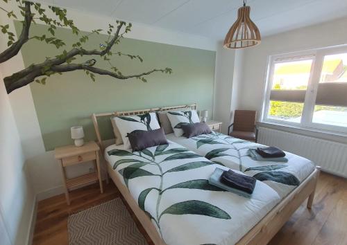 1 dormitorio con 2 camas y un árbol en la pared en Biedebure, en Colijnsplaat