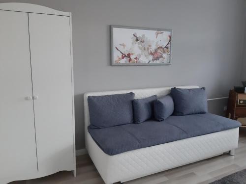 ein weißes Sofa mit blauen Kissen im Wohnzimmer in der Unterkunft Jade Vendégház in Pápa