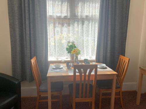 a dining room table with four chairs and a window at St Anne's Road Guest House in Exeter