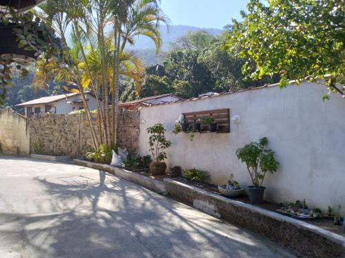 a white building with trees and a wall with plants at Pousada Marimbá in Trindade