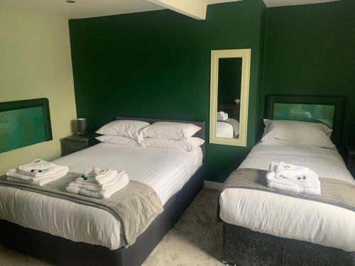 Duas camas num quarto com paredes verdes e espelhos em The Ivy em Lincolnshire