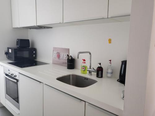 a white kitchen with a sink and a microwave at Cityscape Apartment in Birmingham with Self Checkin in Birmingham
