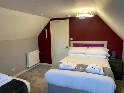 a bedroom with two beds and a red wall at The Ivy in Lincolnshire