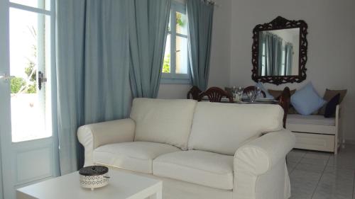 a living room with a white couch and a mirror at Blue & Sea Studios Apartments in Drios