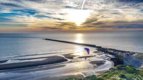 a person flying a kite on a beach near the ocean at La petite maison à deux pas de la mer in Wimille