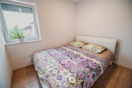 a small bedroom with a bed and a window at Apartments Rozalija in Preddvor