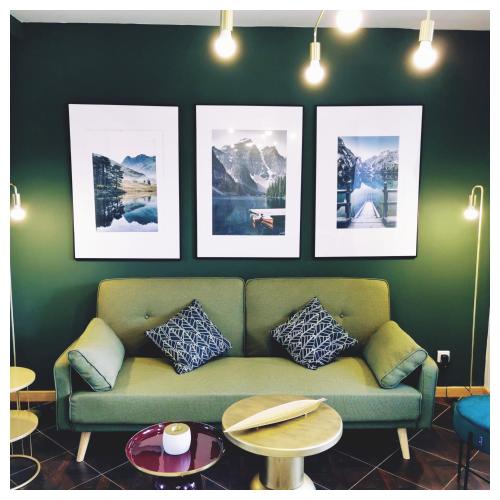 ein Wohnzimmer mit grünem Sofa und Bildern an der Wand in der Unterkunft L'opale in Le Bourg-dʼOisans