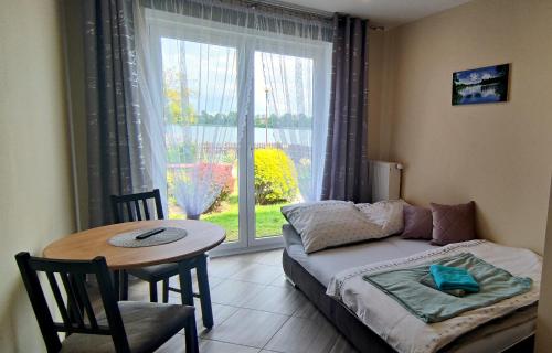een kamer met een bed, een tafel en een raam bij Nad Jeziorem Kochle in Pszczew