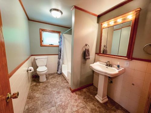 a bathroom with a sink and a toilet and a mirror at 3 Bedroom home outside of Berlin, Patio with Hot Tub! in Millersburg